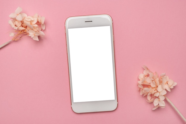 Photo mobile phone mock up and white flowers on pink background.spring pastel colour top view