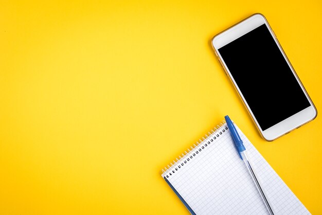 Mobile phone and notebook on yellow