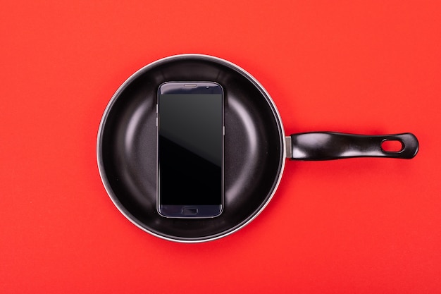 Photo mobile phone in pan isolated on red background