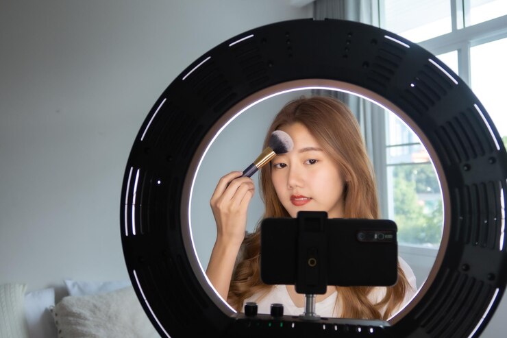 Photo mobile phone photographing young woman applying make-up at home