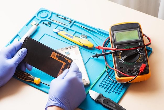 Mobile phone repairing the master remotes the mobile phone\
using tools on a special mat flat lay top view