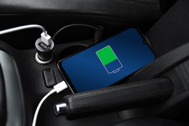 Mobile phone ,smartphone, cellphone is charged ,charge battery\
with usb charger in the inside of car. modern black car\
interior.