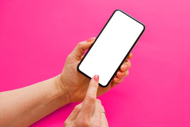 Mobile phone with blank white screen in hands on pink\
background