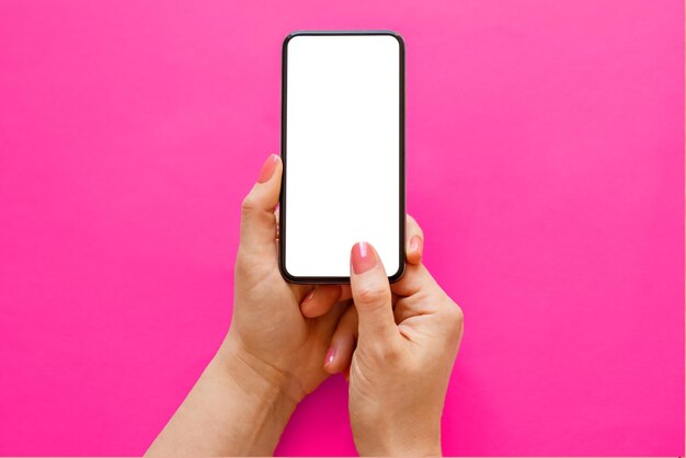 Mobile phone with empty white screen in hands on pink\
background