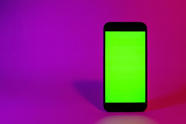 Mobile phone with green screen smartphone mock up neon illumination pink and purple color flat scree...