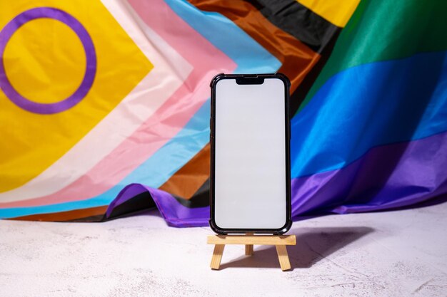 Mobile phone with white screen for copy space on rainbow lgbtqia flag made from silk material