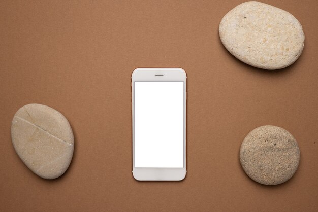 Photo mobile phone with white screen and stone on a light brown.