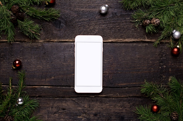 Mobile phone on a wooden table with a Christmas tree and chrismas decoration