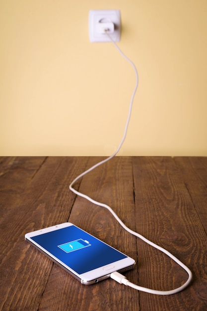 Photo mobile smart phones,phone charging on wooden desk