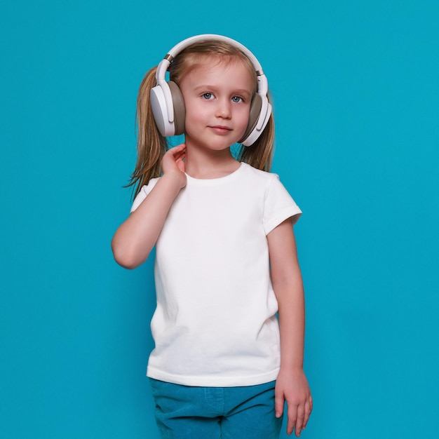 Mocap klein europees meisje in witte t-shirt en koptelefoon op een blauwe achtergrond