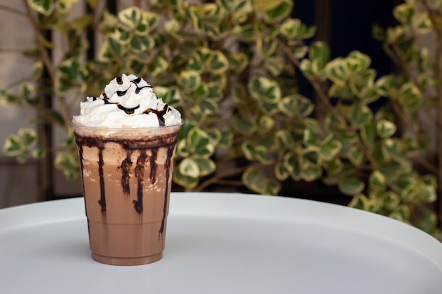 Photo mocha frappe in plastic cup. served with whipping cream and chocolate sauce. freshness drink. favorite caffeine beverage menu.