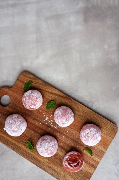 Mochi with strawberry filling on a wooden cutting board on a gray background a traditional asian sweet