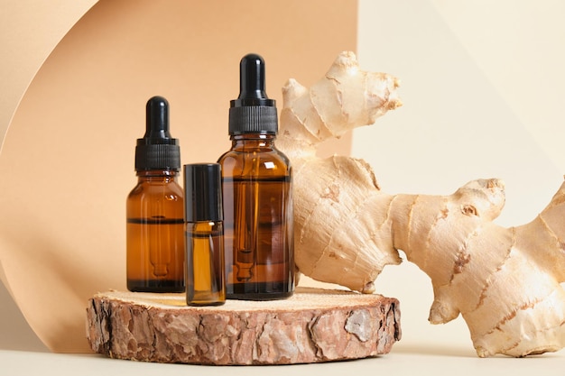 Mock up amber glass dropper bottles and ginger root on beige background copy space natural cosmetic concept, bottles with oil or serum on wooden stand, aroma therapy selective focus