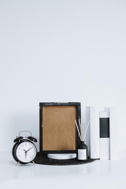 Mock up blank frame poster on podium with books alarm clock and aromatheraphy Workspace office