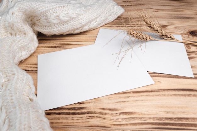 Mock up of a blank sheet on a light wood background with woolen cloth and dry spikelets Copy space