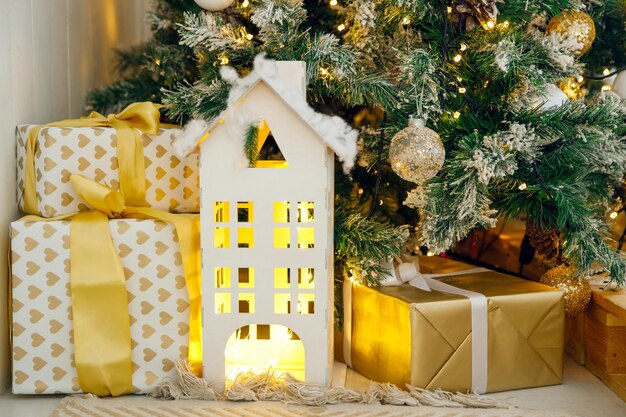 Mock up of cardboard house and Christmas gifts on background of Christmas tree