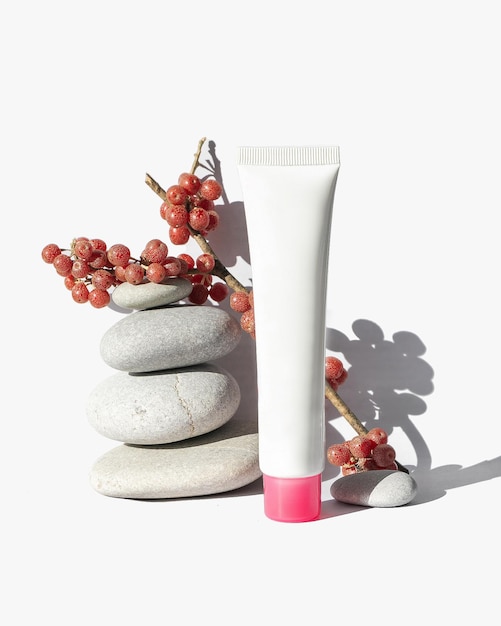 Mock up of cream tube for face cream with stones and berries isolated on whitw