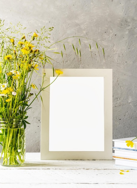 Mock up creation White frame on white wooden table with grey concrete background and flowers