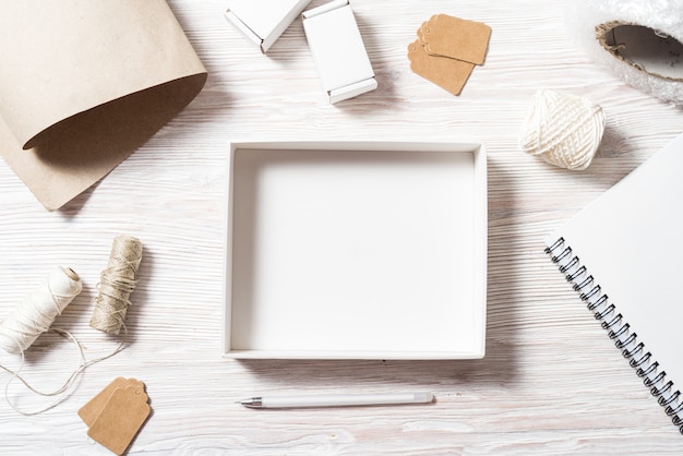 Mock up, empty carton box top view on wooden table with stationary