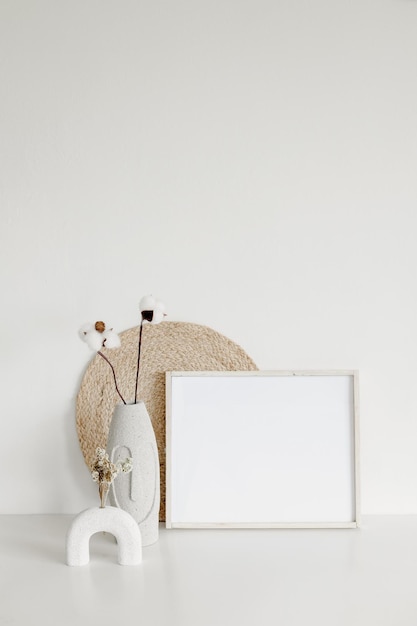 Mock up frame dry plant on vase and wicker Minimalist home interior background in warm tone