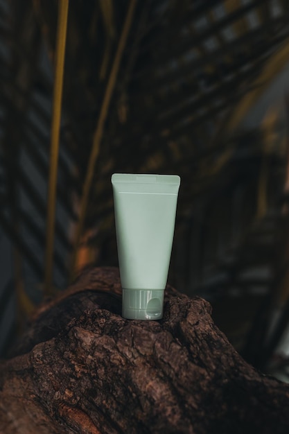 Mock up green tube of face cream against tropical background Skin care product