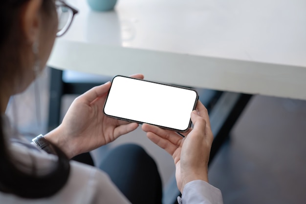 Mock up image Back view of businesswoman holding mobile phones blank screen