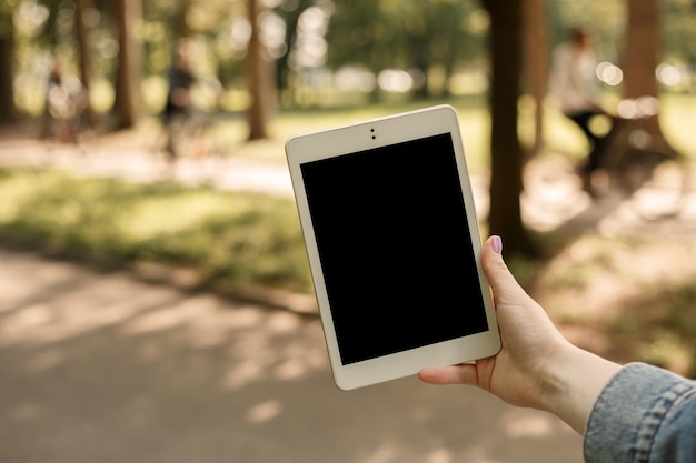 公園でタブレットを保持している女性のモックアップ画像