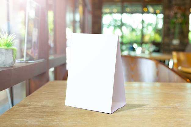 Mock up Label the blank menu frame in Bar restaurant. Stand for booklet with white sheet paper acrylic tent card on table wiht blurred background can inserting the text or picture