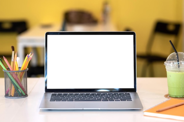 Photo mock up laptop blank white screen with stationery placed at cafe table