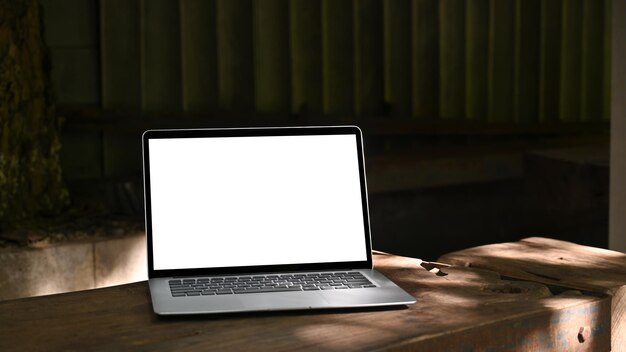 Mock up laptop computer with empty display on wooden table at outdoor