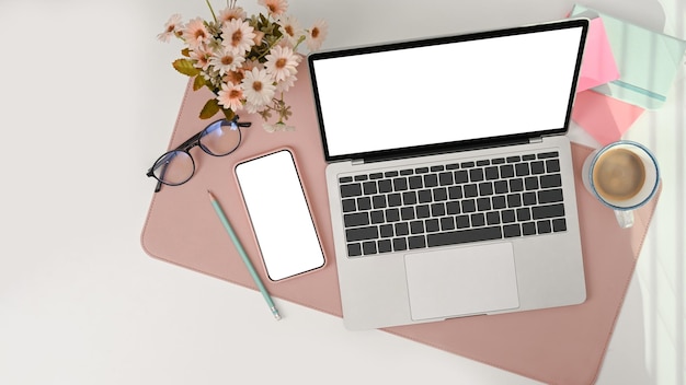 Mock up laptop computer with empty screen and mobile phone on
female office desk