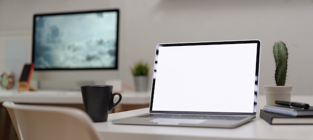 Mock up laptop on office desk with office supplies in modern office room