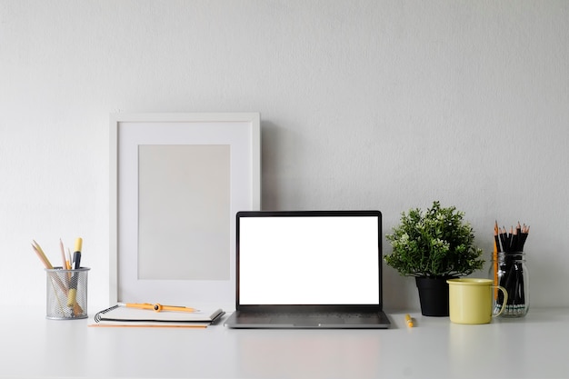 Макет ноутбук на рабочем месте с кружкой кофе, плакат и фоторамки копию пространства офиса.