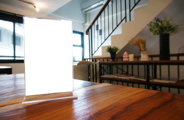 Mock up Menu frame standing on wood table in Bar restaurant cafe. space for text.