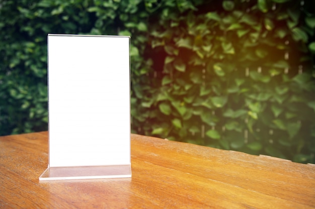 Photo mock up menu frame standing on wood table in bar restaurant cafe. space for text.