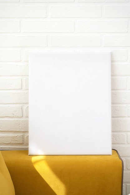 Фото Макет плаката пустой белый холст, серая кирпичная стена и желтая спинка дивана