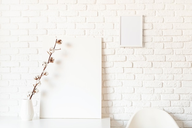 mock up poster frame with cotton branch on white brick wall background