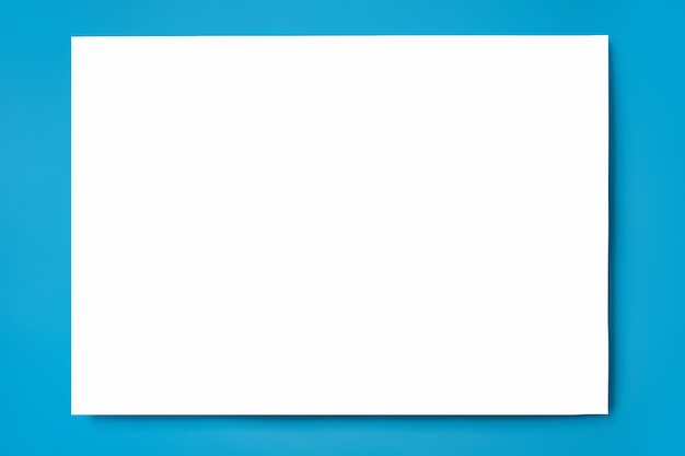 Макет листа белой бумаги формата А4 на синем фоне. Вид сверху. Закройте вверх.
