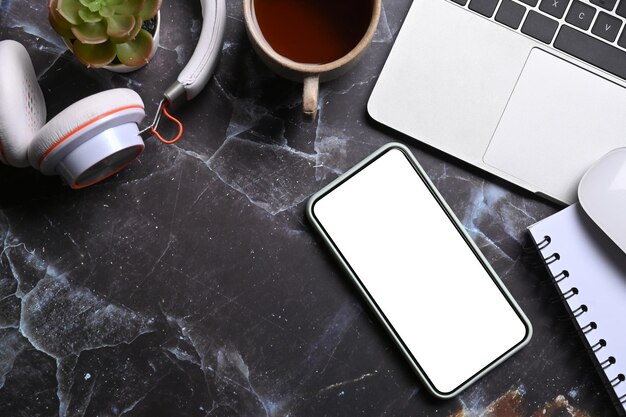 Mock up smart phone with empty screen and laptop on marble background