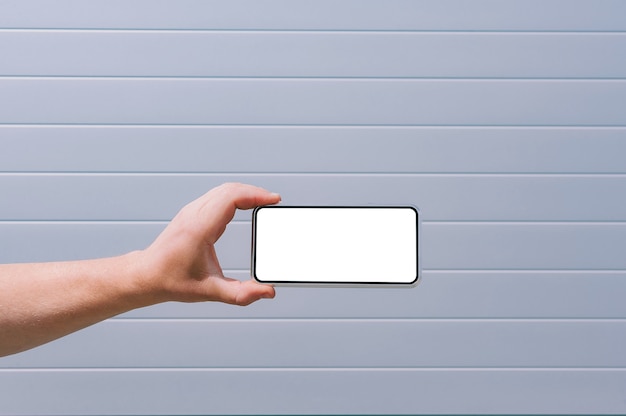 Mock up of a smartphone in a man's hand. against the background of a gray wall.