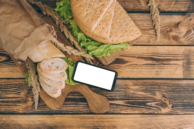 Mock up smartphone on space with fresh bread on a wooden space.