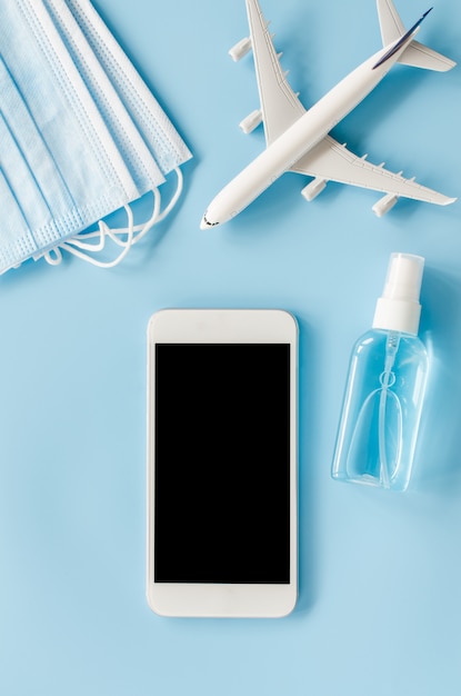 Mock up of smartphone with airplane model, face mask and hand sanitizer spray