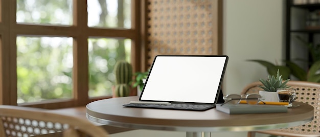 Mock up tablet op ronde houten tafel in comfortabele woonkamer bij het raam