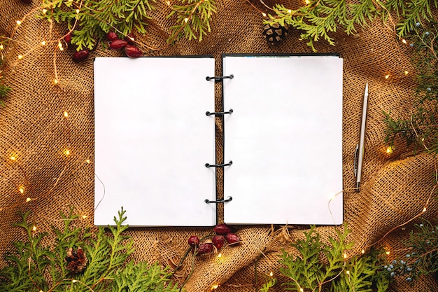 Mock up top view on notebook with festive fir and sackcloth background