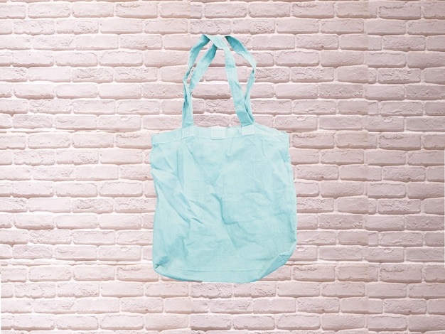 Foto mock up tote bag eco hipster in tessuto di cotone bianco shopping bag in blu. mattoni bianchi e tutto sfondo rustico