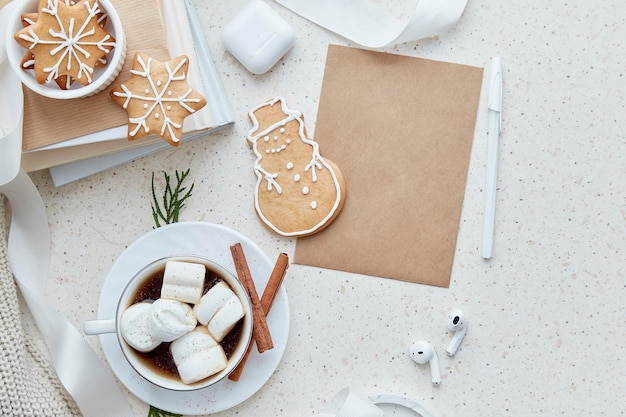 Mock up van crafting envelop in de buurt van oortelefoons Warme cacao met marshmallows en zelfgemaakte gemberkoekjes in de vorm van schattige sneeuwvlokken Esthetische vrouwelijke kerstachtergrond