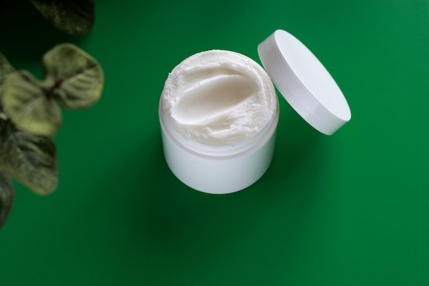 mock up of white jar of cream on a green background, with copy space