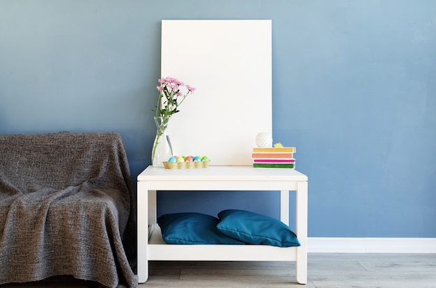Mock up white poster frame on coffee table in blue room. White blank canvas in interior