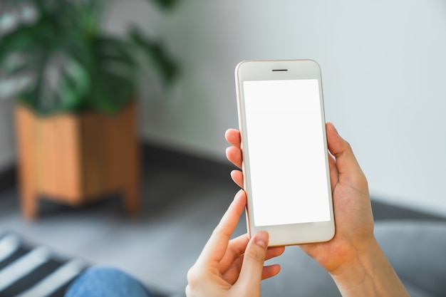 Foto derida su dello smartphone della tenuta della mano della donna e dello schermo in bianco commovente.