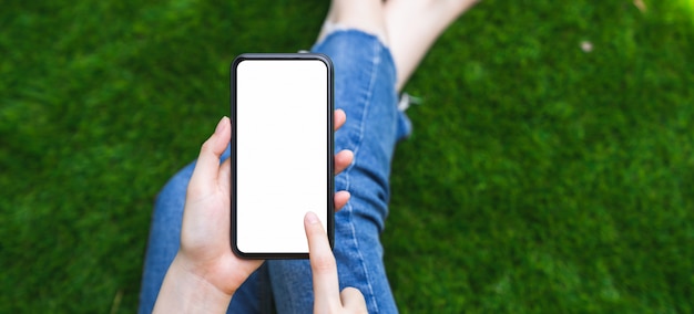 Foto derida su dello smartphone della tenuta della mano della donna e dello schermo in bianco commovente.